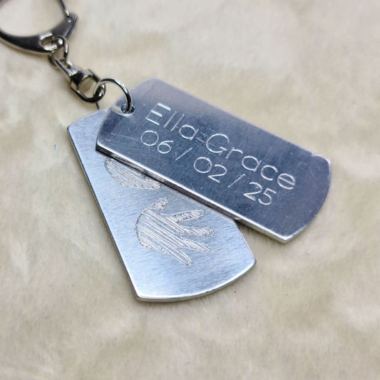 a photo of two metal tags with baby announcement